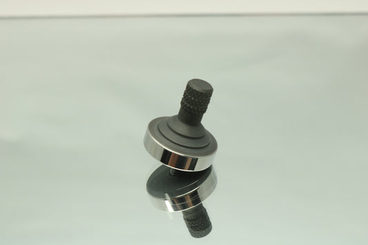 Precision metal spinning top half step in blacked out stainless steel with a polished ring