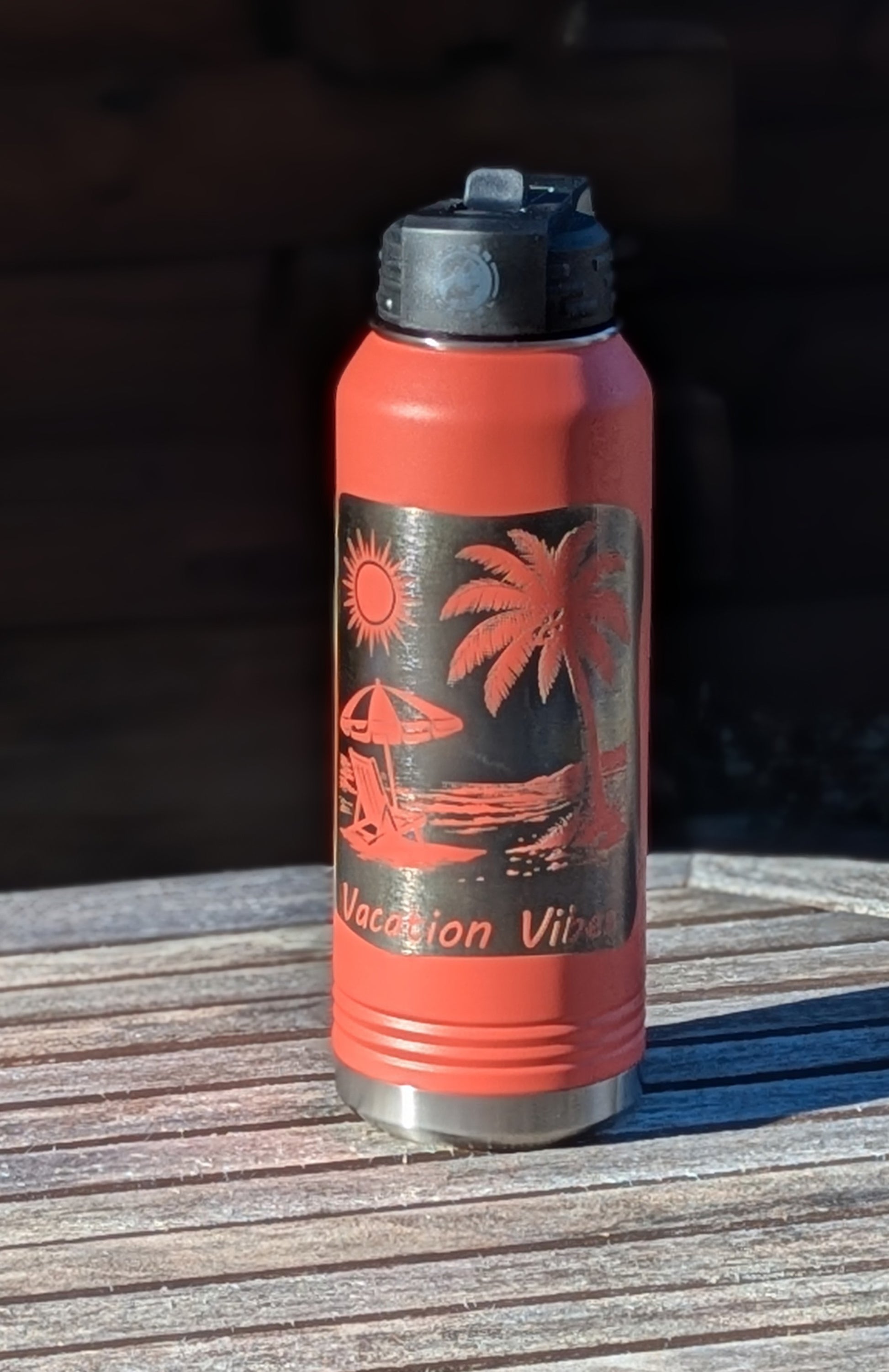 Coral water bottle with tropical design and 'Vacation Vibes' text on a wooden surface.