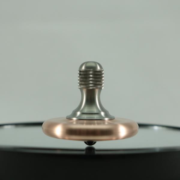 Spinning view of the M3 precision metal spin top by Kemner Design shown here in copper and titanium with a brushed finish