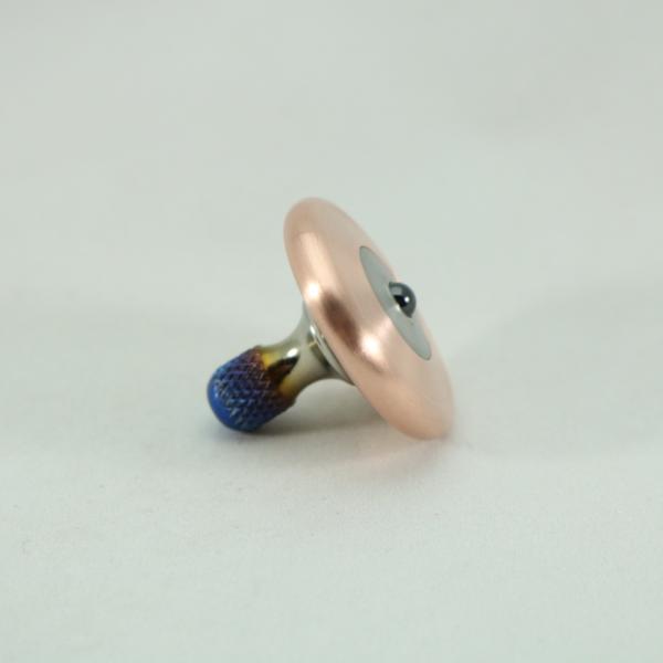 Side view of the brushed copper and flamed titanium M3 precision machined spinning top by Kemner Design
