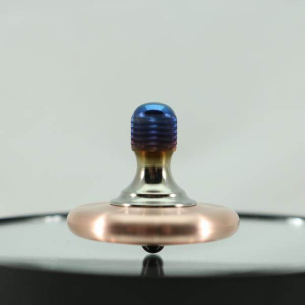 Spinning view of the Kemner Design M3 metal spinning top shown in brushed copper and heat anodized titanium